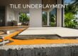 Concrete slab layered with waterproof underlayment, mortar, and partially installed porcelain tiles.